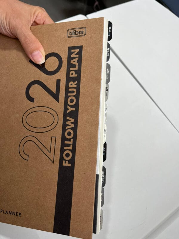Planner Tilibra Kraft Work 2026 personalizado, visto de cima, com as abas dos meses aparecendo e decoração leve em estilo scrapbooking.